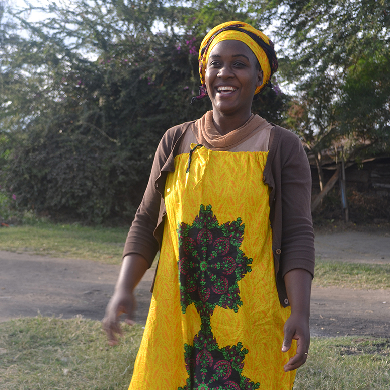 Gladness - A Tanzanian woman smiling wearing a yellow dress